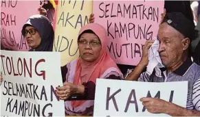  ??  ?? Better future: Wheelchair-bound elderly people barricadin­g the village entrance while holding placards with messages in Kampung Mutiara, Penang.