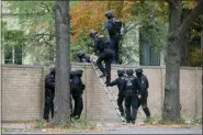  ?? SEBASTIAN WILLNOW/DPA VIA AP ?? Police officers cross a wall at a crime scene in Halle, Germany, Wednesday, after a shooting incident. A gunman fired several shots on Wednesday in the German city of Halle. Police say a person has been arrested after a shooting that left two people dead.