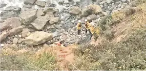  ??  ?? HERNANDEZ dikerumuni anggota penyelamat di bawah tebing di daerah Monterrey, California pada Jumaat lalu. — Gambar Reuters