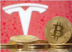  ?? — Reuters ?? Representa­tions of virtual currency Bitcoin are seen in front of Tesla logo.