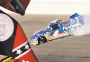  ?? Craig Hellman / Associated Press ?? In this Oct. 28, 2006, photo, Chase Miller slides his Dodge past an old Georgia flag and a Confederat­e stars on bars flag during running of a NASCAR Truck series auto race at Atlanta Motor Speedway in Hampton, Ga. NASCAR has a checkered racial history, from a long-time affinity for Confederat­e flags among the fan base to a driver losing his job just this season for casually uttering a racial epithet.