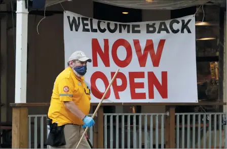  ?? THE ASSOCIATED PRESS ?? A worker passes a sign at a restaurant along the River Walk that has reopened in San Antonio, May 13. Many restaurant­s and stores that were closed due to the COVID-19pandemic have reopened with some restrictio­ns.