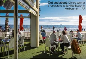  ??  ?? Out and about: Diners seen at a restaurant at St Kilda Beach in Melbourne. — AP