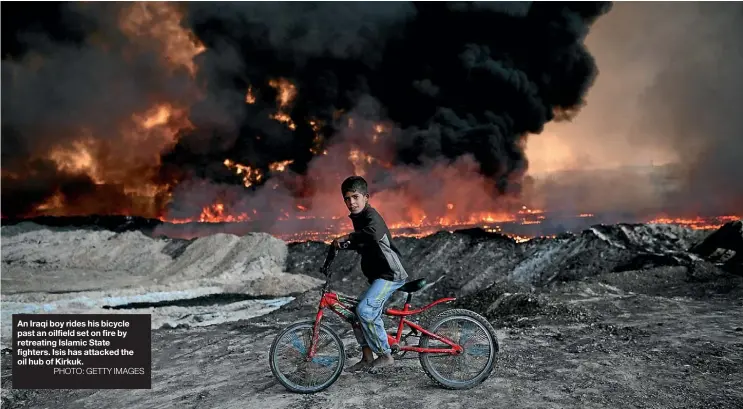  ?? PHOTO: GETTY IMAGES ?? An Iraqi boy rides his bicycle past an oilfield set on fire by retreating Islamic State fighters. Isis has attacked the oil hub of Kirkuk.