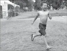  ??  ?? Five-year-old Eli Evans of Pincher Creek runs thorugh a mist station set up to keep people cool during Shelter Me! Party in the Park on Saturday at Galt Gardens.