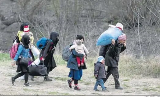  ?? TOLGA BOZOGLU / EFE ?? Una familia de refugiados camina por el río en la ciudad turca de Edirne para llegar a suelo griego a principios de este mes.