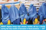  ?? — AFP ?? HERAT: Afghan burqa-clad women receive aid by a charity during the holy month of Ramadan in Herat province.