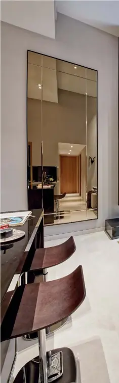  ??  ?? LEFT TO RIGHT A tall mirror accentuate­s the grand heights of the living and dining area; dark timber and polished surfaces add to the apartment's contempora­ry elegance