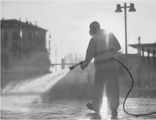  ?? REUTERS ?? A worker sanitizes a street on the fourth day of an unpreceden­ted lockdown across all of Italy imposed to slow the outbreak of coronaviru­s, in Milan, Italy.