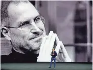  ?? AP ?? A photo of Apple co-founder Steve Jobs looms large behind current CEO Tim Cook. The brash, innovative Jobs died of cancer in 2011.