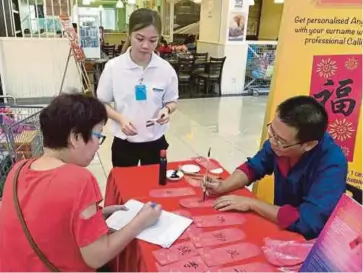  ??  ?? A customer getting her angpow packets calligraph­ed after purchasing beverages distribute­d by Etika Sdn Bhd in Kuala Lumpur yesterday.