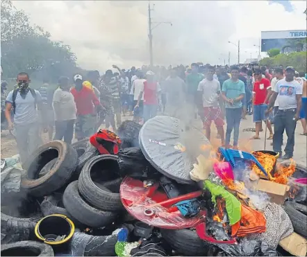  ?? [ Isac Dantes / AFP ] ?? Wütende Brasiliane­r zündeten nach der Vertreibun­g der Venezolane­r Autoreifen an, um die Grenzbrück­e zu sperren.