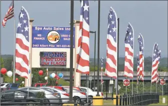 ??  ?? FLAGS OR BANNERS?: Jim Bullard, president of Spa City Auto Inc. says the red, white, and blue banners lining his business at 2443 Albert Pike Road are symbolic of the American flag and should be allowed to stay in place. The city says the banners...