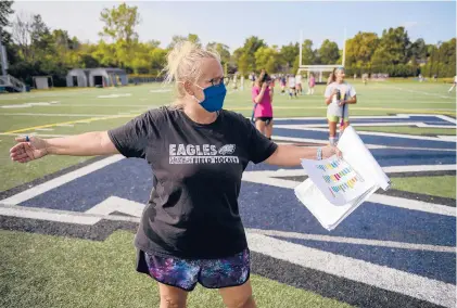  ?? MARK MIRKO/HARTFORD COURANT ?? Holding a chart with color-coded player pairs, Wethersfie­ld High School field hockey coach Colleen Budaj coaches during a socially distanced practice on Sept. 4.