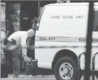  ?? AP PHOTO ?? A law enforcemen­t investigat­or puts protective covers over his feet Monday before entering a building that was the scene of mass shooting at The Jacksonvil­le Landing in Jacksonvil­le, Fla.