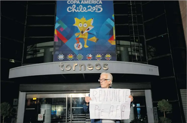  ?? — PHOTOS: THE ASSOCIATED PRESS FILES ?? A man holds a sign reading ‘Resign Argentine Soccer Associatio­n president’ in front of a sports marketing company in Buenos Aires in late May.