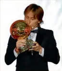  ??  ?? El croata Luka Modric da un beso al Balón de Oro durante la ceremonia.