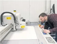  ??  ?? Industrial designer Sam Huffman keeps a watchful eye as a machine cuts out a pizza box at the centre.