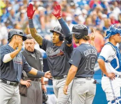  ?? THE ASSOCIATED PRESS ?? The Atlanta Braves’ Johan Camargo, center, celebrates with teammates Kurt Suzuki, left, and Charlie Culberson after hitting a grand slam against the Toronto Blue Jays on Tuesday in Toronto.
