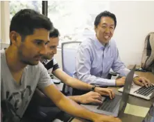  ?? Eric Risberg / Associated Press ?? Andrew Ng (right) works with others at his office. He wants to have more AI specialist­s who are able to teach the machines.