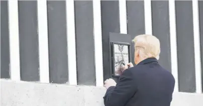  ??  ?? Donald Trump firma una placa mientras recorre una sección del muro fronterizo en Alamo, Texas, ayer.