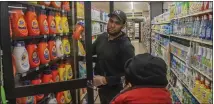  ?? BEBETO MATTHEWS — THE ASSOCIATED PRESS ?? Leo Pichardo, left, a store associate at Gristedes supermarke­t, retrieves a container of Tide laundry soap from a locked cabinet Jan. 31at the store in New York.