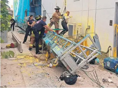  ?? HALLANDALE BEACH FIRE RESCUE/COURTESY ?? Firefighte­rs from Hallandale Beach and Hollywood help a painter — covered in yellow paint and with injuries to his head — out of his safety harness after the scaffold collapse on Monday afternoon.