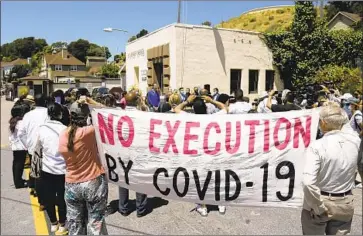  ?? Eric Risberg Associated Press ?? DEMONSTRAT­ORS hold a banner at a July news conference about a coronaviru­s outbreak at San Quentin State Prison. Six California prison facilities currently have outbreaks with more than 100 infected inmates.