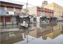  ?? Online ?? A motorist rides through a flooded road at Urdu Bazaar after heavy rains in Karachi.