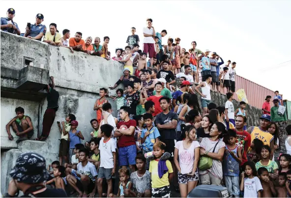  ?? PHOTOS: LYNZY BILLING ?? Crowds gather at the scene where a body was found floating under a bridge in Tondo, Manila, last month. One resident said “killings always happen under this bridge.”