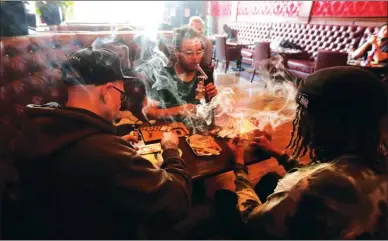  ?? The Associated Press ?? Rick Thompson, clockwise from left, Keith Baskervill­e and Xavier Baskervill­e smoke marijuana while sitting in a booth in the smoking lounge at Barbary Coast Dispensary in San Francisco. San Francisco plans to issue more permits for marijuana smoking...