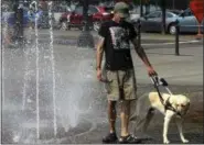  ?? DON RYAN — THE ASSOCIATED PRESS ?? Braden Dashney tries to coax his reluctant service dog, Fonzie, into the rolling waters of Salmon Street Springs fountain in Portland, Ore., Thursday.