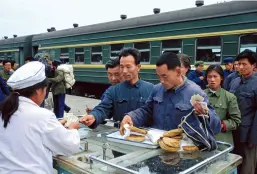  ??  ?? Des gens font la queue pour acheter des aliments dans une gare le long de la ligne de chemin de fer Beijing-Chengde, en 1977.