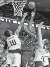  ?? AP/SAM CRAFT ?? Arkansas forward Trey Thompson (middle) puts up a shot over Texas A&M’s Tonny Trocha-Morelos (10) and Alex Caruso during the first half of the Razorbacks’ 92-69 loss to the No. 20 Aggies on Saturday in College Station, Texas.