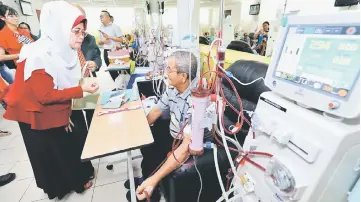  ??  ?? Fatimah speaks to a patient who is undergoing dialysis at the centre.