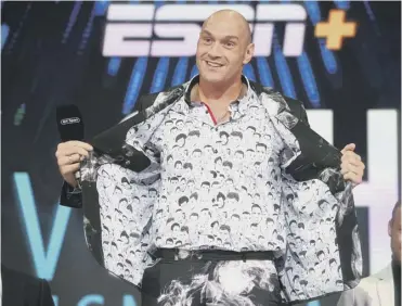  ??  ?? 0 Tyson Fury wears a shirt and jacket featuring the faces of great heavyweigh­ts, including his own.