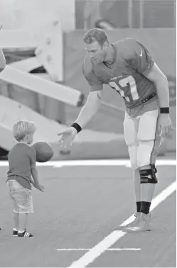  ?? AP Photo/Lynne Sladky ?? ■ Miami Dolphins quarterbac­k Ryan Tannehill plays with his son, Steel, at the team’s training camp Monday in Davie, Fla. Tannehill just celebrated his 30th birthday but says he feels like he’s 25, and that includes his surgically repaired left knee.