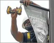  ?? NATRICE MILLER/AJC ?? Alpha Graphics’ Kyle Williams puts up a banner on Jimmy Carter Boulevard in Norcross on Monday.