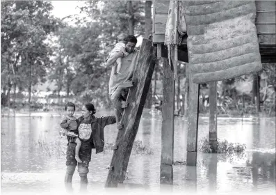  ?? Photo: AFP ?? A Laotian couple carries their children from their home in the flooded area in Sanamxai, Attapeu province, on Thursday. Rescuers battled fresh rains on Thursday to reach scores of people who remain missing following the collapse of a dam in southern Laos that unleashed a torrent of water, washing away whole villages and killing at least 26 people.