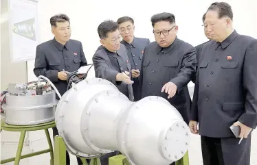  ?? AFP PHOTO ?? RAMPING IT This undated picture released by North Korea’s official Korean Central News Agency (KCNA) on September 3, 2017 shows North Korean leader Kim Jong-Un (center) looking at a metal casing with two bulges at an undisclose­d location.