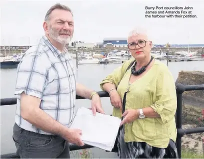  ??  ?? Burry Port councillor­s John James and Amanda Fox at the harbour with their petition.