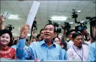  ?? MANAN VATSYAYANA / AFP ?? Cambodia's Prime Minister Hun Sen (center) prepares to cast his vote during the general election as his wife Bun Rany (left) looks on in Phnom Penh on Sunday.