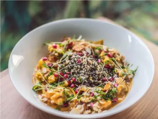  ??  ?? Coconut, sweet potato and pumpkin curry with quinoa, tomato, pomegranat­e and coconut flakes