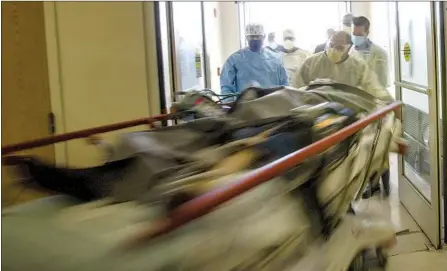  ?? Gina Ferazzi Los Angeles Times ?? EMERGENCY ROOM medical staff rush a trauma patient to the exam area after he arrived via Mercy Air at Riverside University Health System in Moreno Valley. The availabili­ty of beds in intensive care units in Southern California remained at zero Sunday.