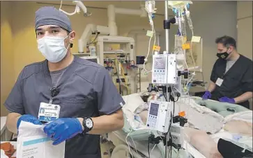  ?? ?? RICKY MIRANDA, left, a new nurse at Arrowhead Regional Medical Center, with preceptor Brian Stevenson. “Our staff is working ... extra days just to try and pick up for those who are out sick,” an official said.