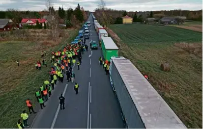  ?? DAMIEN SIMONART/AFP VIA GETTY IMAGES ?? Trucks waited near the Polish-Ukrainian border crossing in Dorohusk, Poland, as Ukrainian drivers protested and asked Polish police officers to let them pass to Ukraine.