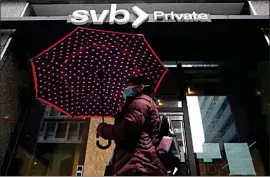  ?? JEFF CHIU / AP ?? A pedestrian carries an umbrella while walking past a Silicon Valley Bank Private branch in San Francisco on Tuesday.
