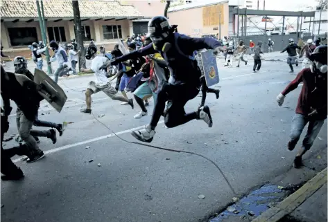  ?? ARIANA CUBILLOS/AP ?? Anti-government protesters run from advancing Venezuelan Bolivarian National Guard officers Wednesday on the first day of a 48-hour general strike in protest of government plans to rewrite the constituti­on, in Caracas, Venezuela. President Nicolas...