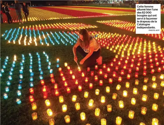  ?? PHOTO AFP ?? Cette femme allumé hier l’une des 82 000 bougies qui ont servi à façonner le drapeau de la Catalogne indépendan­te.