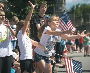  ?? Stephanie Strasburg/Post-Gazette ?? Isabella Coyne, 7, of Ross, front, and her sister, Hailey, 10, center, reach out to catch candy Monday as they watch the Lawrencevi­lle Memorial Day parade. The girls’ family grew up in Lawrencevi­lle and returns for the parade annually.